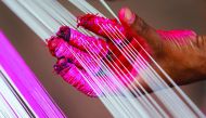 A worker applies colour to strings which will be used to make kites, alongside a road in Ahmedabad, yesterday. The 2017 Kite Festival Celebration is set to mark from January 7 to 15.
