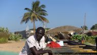 Gambian Ansu Sanyang poses next to a dugout on the beach in the village of Sanyang on December 4, 2016. Ansu Sanyang was ready. Sick of providing so little for his parents and sisters with any work he could find, the young Gambian resolved to take the mig