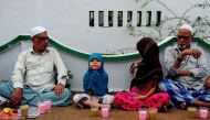 A young child sits with her guardians as they prepare to break the fast with the Iftar meal during Ramadan at The Wallajah Big Mosque in Chennai on July 1, 2016 (Reuters) 