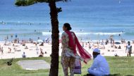 A couple takes shelter from the heat in the shade of a tree as they look out over Sydney's Bondi Beach on February 11, 2017. AFP / William WEST