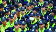 Police stand outside Dhammakaya Buddhist temple while followers defy orders to leave its grounds to enable police to seek out their former abbot in Pathum Thani, Thailand, yesterday.