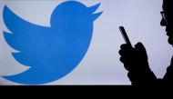 A picture shows a man holding a cellphone in front of a twitter logo in Ankara, Turkey on March 16, 2017. ( Gökhan Balc? - Anadolu Agency )