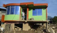 A man stands in the doorway of his house, which was damaged by a mudslide caused by heavy rains in Mocoa, Putumayo department, Colombia on April 5, 2017.  AFP / LUIS ROBAYO
