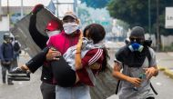 A young woman who was overcome by tear gas shot by tiot police is carried away by fellow demonstrators when opposition activists clashed with riot police in Caracas on April 10, 2017.  AFP / FEDERICO PARRA
