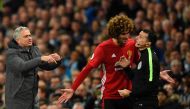 Manchester United's Portuguese manager Jose Mourinho (L) indicates he wants to make a substitution as Manchester United's Belgian midfielder Marouane Fellaini (C) talks to fourth official Neil Swarbrick (R) after Fellaini was sent off during the English P