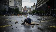 An masked opposition activist sits on the floor during a blockade to protest against Venezuelan President Nicolas Maduro in Caracas, on July 19, 2017. Venezuela's military chiefs reaffirmed their loyalty to President Nicolas Maduro on Wednesday by saying 