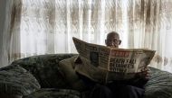 Phillip Mabelane, paging through a newspaper from the period, has been battling for 40 years for an investigation into the truth behind his son's 1977 death under apartheid./ AFP.