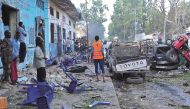 A file photo of people standing among damages at the scene of a blast after two car bombs exploded in Mogadishu on October 28, 2017.  AFP / Mohamed ABDIWAHAB