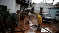 Locals remove mud from the entrance of their house, following flash floods which hit the town of Mandra, Greece, November 18, 2017. REUTERS/Costas Baltas.