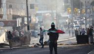 A Palestinian holds a Palestinian flag as Israeli security forces intervene in a demonstration against U.S. President Donald Trump's recognition of Jerusalem as Israel's capital, in Bethlehem, West Bank on December 10, 2017. ( Mamoun Wazwaz - Anadolu Agen