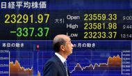 A pedestrian walks past a stock market indicator board in Tokyo, Japan, 30 January 2018. EPA / FRANCK ROBICHON