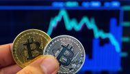 A picture taken on February 6, 2018 shows a person holding a visual representation of the digital crypto-currency Bitcoin, at the 