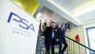 French Economy Minister Bruno Le Maire (R) walks with chairman of the managing board of French carmaker PSA Peugeot Citroen Carlos Tavares during a visit to the PSA car plant in Mulhouse on February 23, 2018.  AFP / Sebastien Bozon 