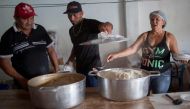 A Venezuelan immigrant (C) helps Brazilian neighborhoods to prepare meals for the Venezuelan refugees living at Simon Bolivar Square, in Boa Vista, Roraima, Brazil, on February 25, 2018.  AFP / Mauro Pimentel
