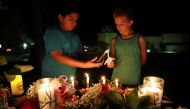 Christian Cardenas 10, helps Jaydon Johnson 8, light a candle during a vigil for the victims of a shooting at Santa Fe High School that left several dead and injured in Santa Fe, Texas, U.S., May 18, 2018. REUTERS/Pu Ying Huang