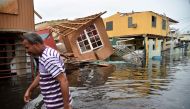 (FILE PHOTO) In this file photo taken on September 21, 2017 a man walks past destroyed homes in Catano, Puerto Rico, on September 21, 2017.  AFP / HECTOR RETAMAL
