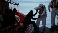 A migrant, part of a group intercepted aboard a dinghy off the coast in the Mediterranean Sea, is helped by a rescuer after arriving on a rescue boat at the port of Malaga, Spain June 22, 2018. REUTERS/Jon Nazca
