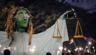 Romanians chant slogans as they stand next to a giant statue picturing the symbol of justice during a demonstration to protest against the government on August 11, 2018, in Bucharest. AFP / Daniel Mihailescu
 