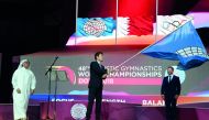 FIG President Morinari Watanabe (centre) waves the FIG flag after receiving the same from Ali Al Hitmi (left), the Executive Director of the Organising Committee of Doha Worlds and also President of the Qatar Gymnastics Federation during the closing cerem