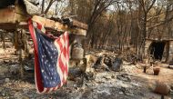 An American flag hangs at a burned out mobile home park in Paradise, California on November 18, 2018. The family lost a home in the same spot to a fire 10 years prior. / AFP / Josh Edelson 