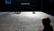 A man uses his phone as he sits in front of a Huawei shop in Beijing, December 11, 2018. Reuters/Thomas Peter