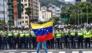 A member of the Venezuela opposition gestures showing a national flag in front of National policemen during a demonstration in Caracas on July, 27, 2016 (AFP) 