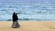 In this picture taken on April 25, 2019 a Sri Lankan woman walks along a beach with her child in Kattankudy. AFP/Lakruwan Wanniarachchi