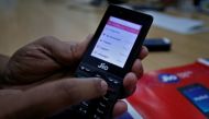 FILE PHOTO: A sales person displays features of JioPhone as he poses for a photograph at a store of Reliance Industries' Jio telecoms unit, on the outskirts of Ahmedabad, India, September 26, 2017. REUTERS/Amit Dave/File Photo