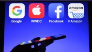 A smartphone being operated in front of GAFA logos,  acronym for Google Apple Facebook and Amazon, as background in Hédé-Bazouges, western France, on September 28, 2017. AFP / Damien Meyer