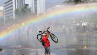A demonstrator lifts his bike in the air during clashes with riot police in Santiago on October 24, 2019 after a week of street violence which erupted against a now suspended metro fare hike but spiralled into general discontent.  AFP / Martin Bernetti  