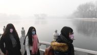 Chinese women wear masks on a heavily polluted day in Beijing on January 1, 2017. AFP / Greg Baker