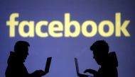 Silhouettes of laptop users are seen next to a screen projection of Facebook logo in this picture illustration, March 28, 2018. Reuters / Dado Ruvic