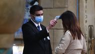 A staff member checks the temperature of a guest entering at a hotel in Macau on January 22, 2020, after the former Portuguese colony reported its case of the virus that originated from Wuhan in China. AFP / Anthony Wallace