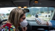 A health worker, controls the temperature of a woman in a sanitary barrier during the coronavirus disease (COVID-19) outbreak, in Sao Sebastiao, Sao Paulo state, Brazil, April 18, 2020. REUTERS/Roosevelt Cassio