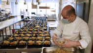 :Food is prepared by Okan Kizilbayir, Sous Chef along with Le Bernardin chef and co-owner Eric Ripert as they are preparing meals for health care workers as part of the World Central Kitchen charity at his flagship New York restaurant in New York City on 