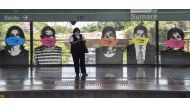 A woman awaits for the subway standing next to the Brazilian artist Alex Flemming work 
