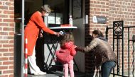 A teacher takes the temperature of a child at the entrance of a flemish primary school during its reopening as a small part of Belgian children head back to their schools with new rules and social distancing during the outbreak of the coronavirus disease 