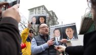 (FILES) In this file photo taken on March 06, 2019 Louis Huang of Vancouver Freedom and Democracy for China holds photos of Canadians Michael Spavor and Michael Kovrig, who are being detained by China, outside British Columbia Supreme Court, in Vancouver,