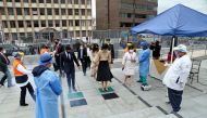 Handout picture released by Ecuador's National Assembly showing the new Vice-President of Ecuador, Maria Alejandra Munoz (C) disinfection her shoes against the spread of the COVID-19 novel coronavirus upon arriving at her inauguration at the National Asse