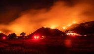 In this long exposure photograph, firefighters monitor flames as they skirt a hillside near a residential area during the Apple fire in Banning, California on August 1, 2020. 4,125 acres have burn in Cherry Valley, about 2,000 people have received evacuat