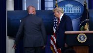 TOPSHOT - US President Donald Trump is being removed by a member of the secret service from the Brady Briefing Room of the White House in Washington, DC, on August 10, 2020. Secret Service guards shot a person, who was apparently armed, outside the White 