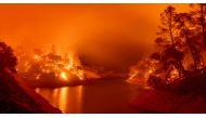 In this long exposure photograph, flames consumes both sides of a segment of Lake Berryessa during the Hennessey fire in the Spanish Flat area of Napa, California on August 18, 2020.  / AFP / JOSH EDELSON