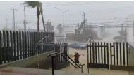 A woman walks under her umbrella while a car moves along a flooded road during Hurricane Genevieve in Los Cabos, Baja California Del Sur, Mexico August 19, 2020, in this still image obtained from video provided on social media. 