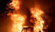 A man on a bike rides past a city truck on fire outside the Kenosha County Courthouse in Kenosha, Wisconsin, U.S., during protests following the police shooting of Black man Jacob Blake August 23, 2020. The picture was taken on August 23, 2020. Mike De Si