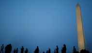 Activists stand with American flags at sunrise to memorialize victims of the coronavirus disease (COVID-19) outbreak, near the Washington Monument in Washington, U.S., August 27, 2020. REUTERS/Tom Brenner

