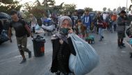 Refugees and migrants from the destroyed Moria camp carry their belongings as they walk towards a new temporary camp, on the island of Lesbos, Greece, September 18, 2020. REUTERS/Elias Marcou