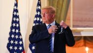 U.S. President Donald Trump pulls off his protective face mask as he poses atop the Truman Balcony of the White House after returning from being hospitalized at Walter Reed Medical Center for coronavirus disease (COVID-19) treatment, in Washington, U.S. O
