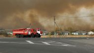 Fire trucks are seen on the road as smoke rises from the site of a fire at an ammunition depot in Ryazan Region, Russia October 7, 2020. Russian Emergencies Ministry in Ryazan Region/Handout via REUTERS 