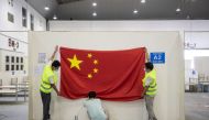 (FILES) In this file photo workers remove a national flag as they demolish installations at Wuhan's largest makeshift hospital built to treat patients infected by the COVID-19 coronavirus in China's central Hubei province on July 29, 2020. China OUT / AFP