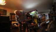 Alonso Toro, a professional musician who worked in television and advertising, looks at his son Elias who wears a dinosaur face mask made by him, during the coronavirus disease (COVID-19) pandemic, in Caracas, Venezuela August 26, 2020. Reuters/Fausto Tor